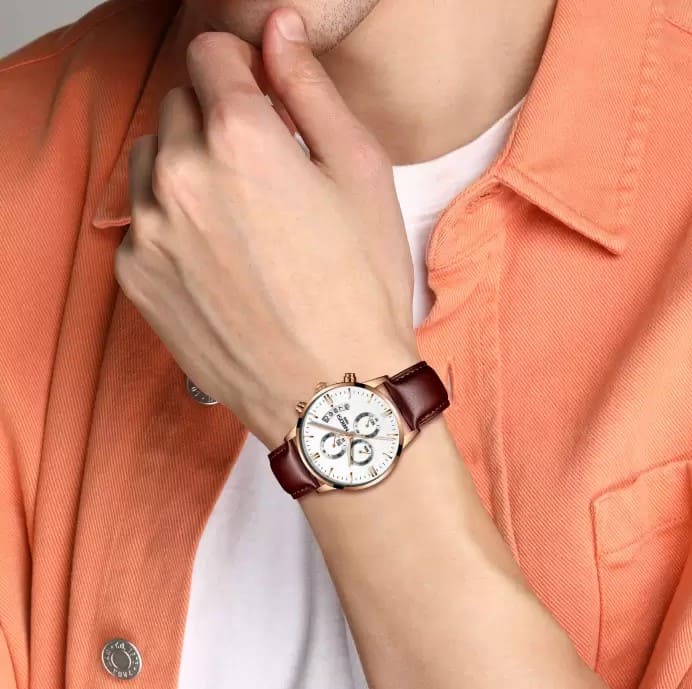 Relógio Social Masculino Nibosi 2309 com pulseira de couro marrom e visor branco no pulso de um homem