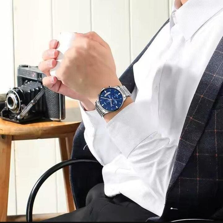 Relógio Nibosi Masculino 2309 Com Pulseira de Aço Inoxidável Prata e Visor Azul no Pulso de um Homem