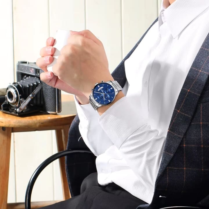Relógio Nibosi Masculino 2309 Com Pulseira de Aço Inoxidável Prata e Visor Azul no Pulso de um Homem