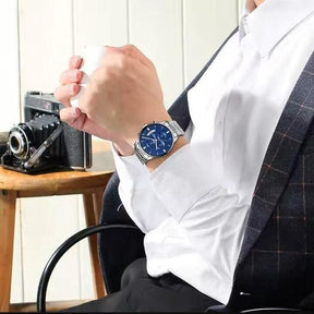 Relógio Nibosi Masculino 2309 Com Pulseira de Aço Inoxidável Prata e Visor Azul no Pulso de um Homem