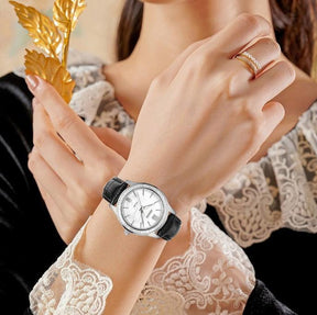 Relógio feminino Nibosi Nataly com pulseira de couro preto e mostrador branco no pulso de uma mulher