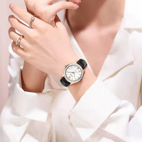 Relógio feminino Nibosi Nataly com pulseira de couro preta e mostrador branco com rosé no pulso de uma mulher