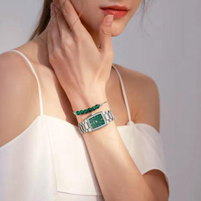 Relógio feminino minimalista pequeno com pulseira prata e visor verde no pulso de uma mulher